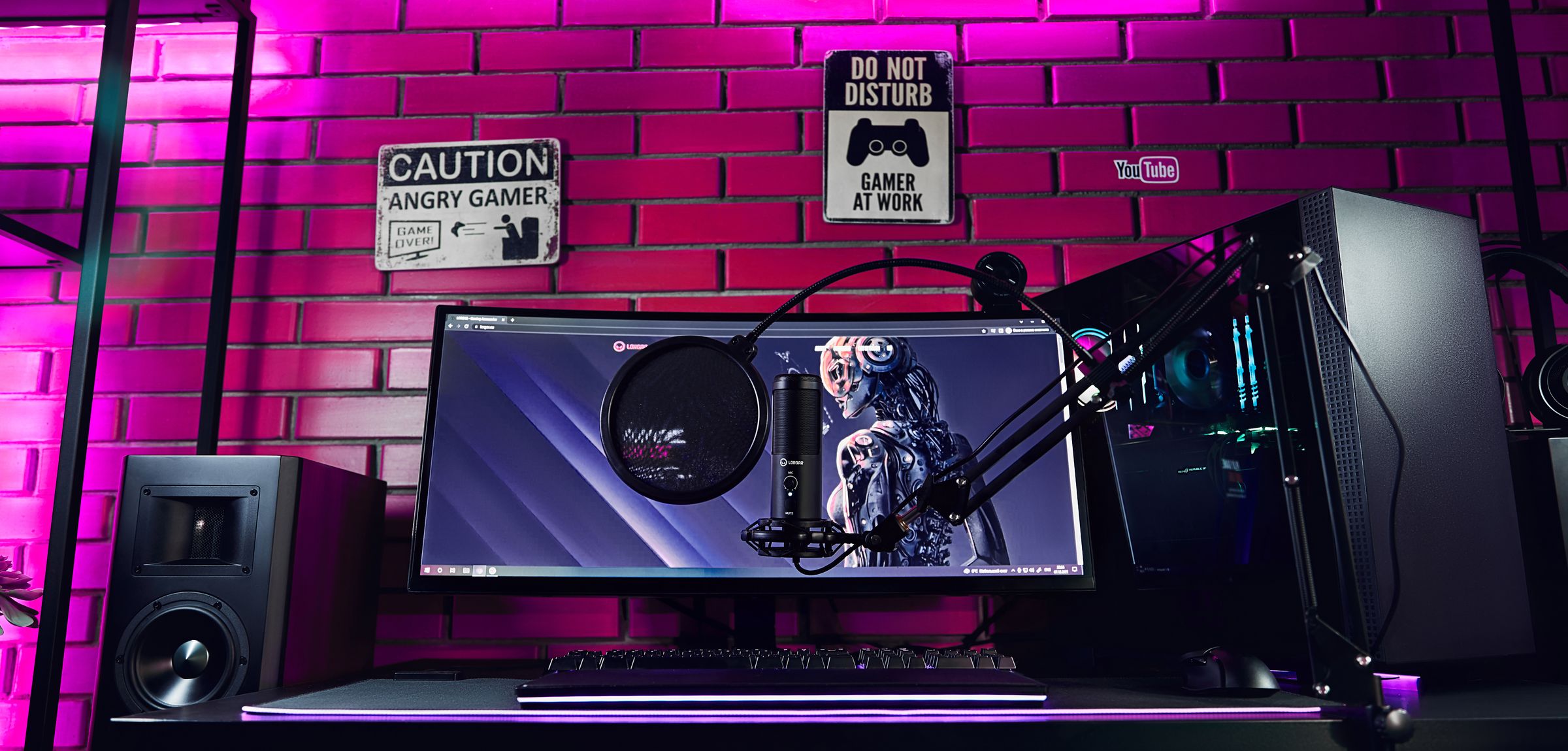 A LORGAR gaming setup in purple and pink light: monitor, microphone, keyboard, speakers and computer