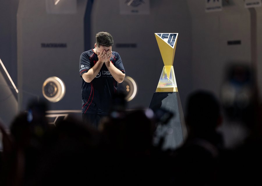 A player covering his face with his hands beside the world championship trophy
